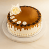 Round caramel cake with white rose decoration, ideal for celebrations in Guwahati