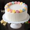 Pastel rose vanilla cake with colorful floral icing decorations, available for birthday and anniversary delivery in Guwahati.