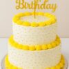 Elegant two-tier yellow birthday cake with golden icing, perfect for celebrations, available for online delivery in Guwahati.