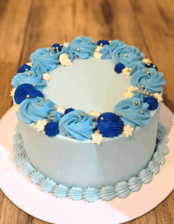 Blue Bliss Birthday Cake with royal blue and sky-blue cream swirls topped with golden pearls on a wooden background.